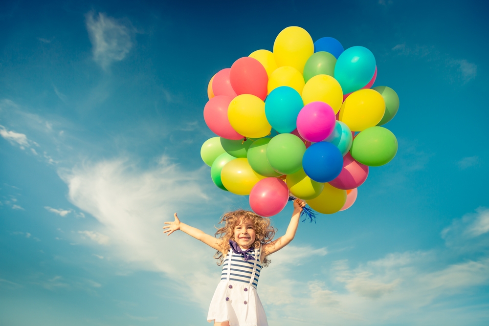 Happy child jumping with colorful toy balloons